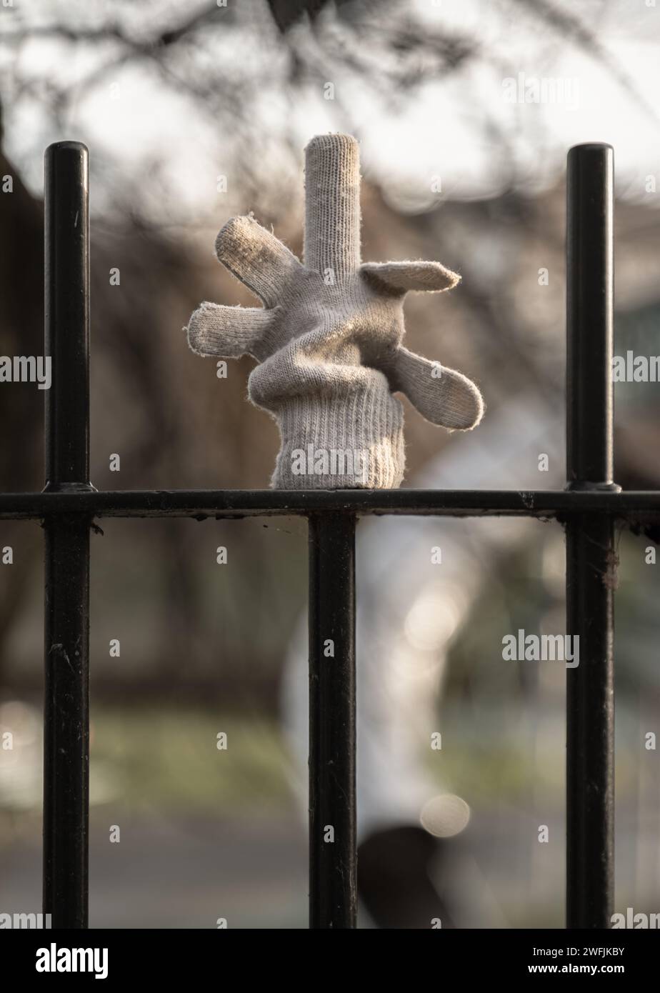 glove hanging on a metal fence railing with the middle finger