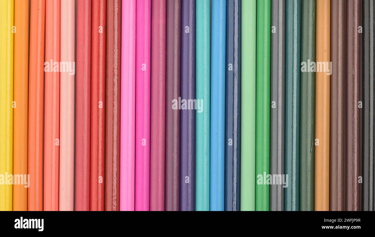 Colour spectrum background. Coloured pencils bodies arranged in a row. Wooden texture. Close up. Stock Photo