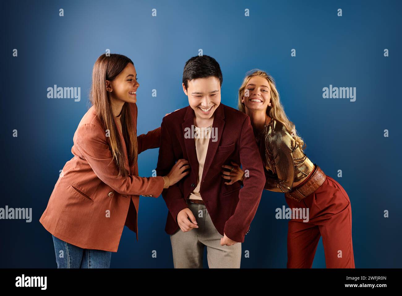 jolly multiracial teenagers in bright attires having good time on blue ...