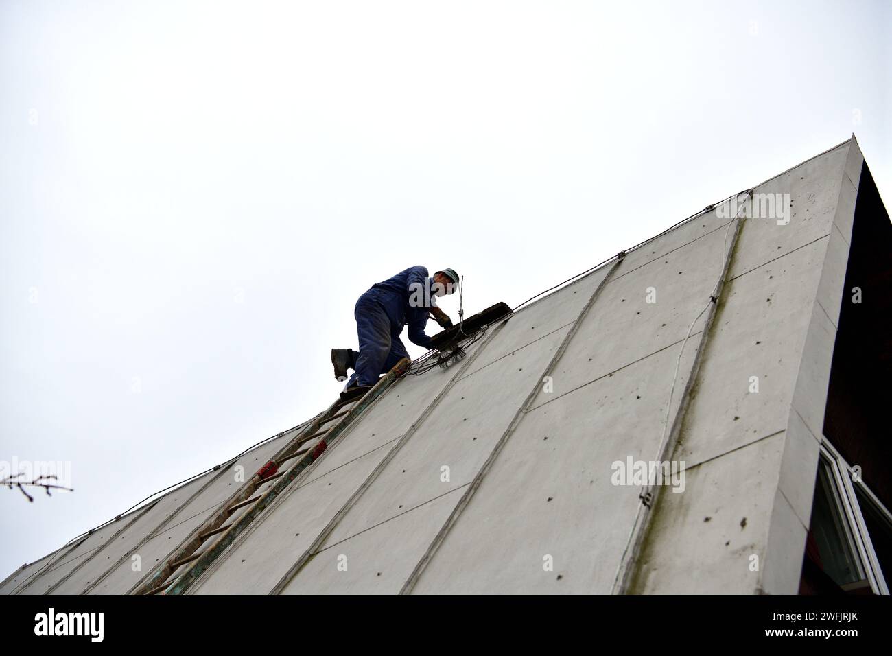 Roof repairman and the traditional way of repairing the roof of the cottage Stock Photo