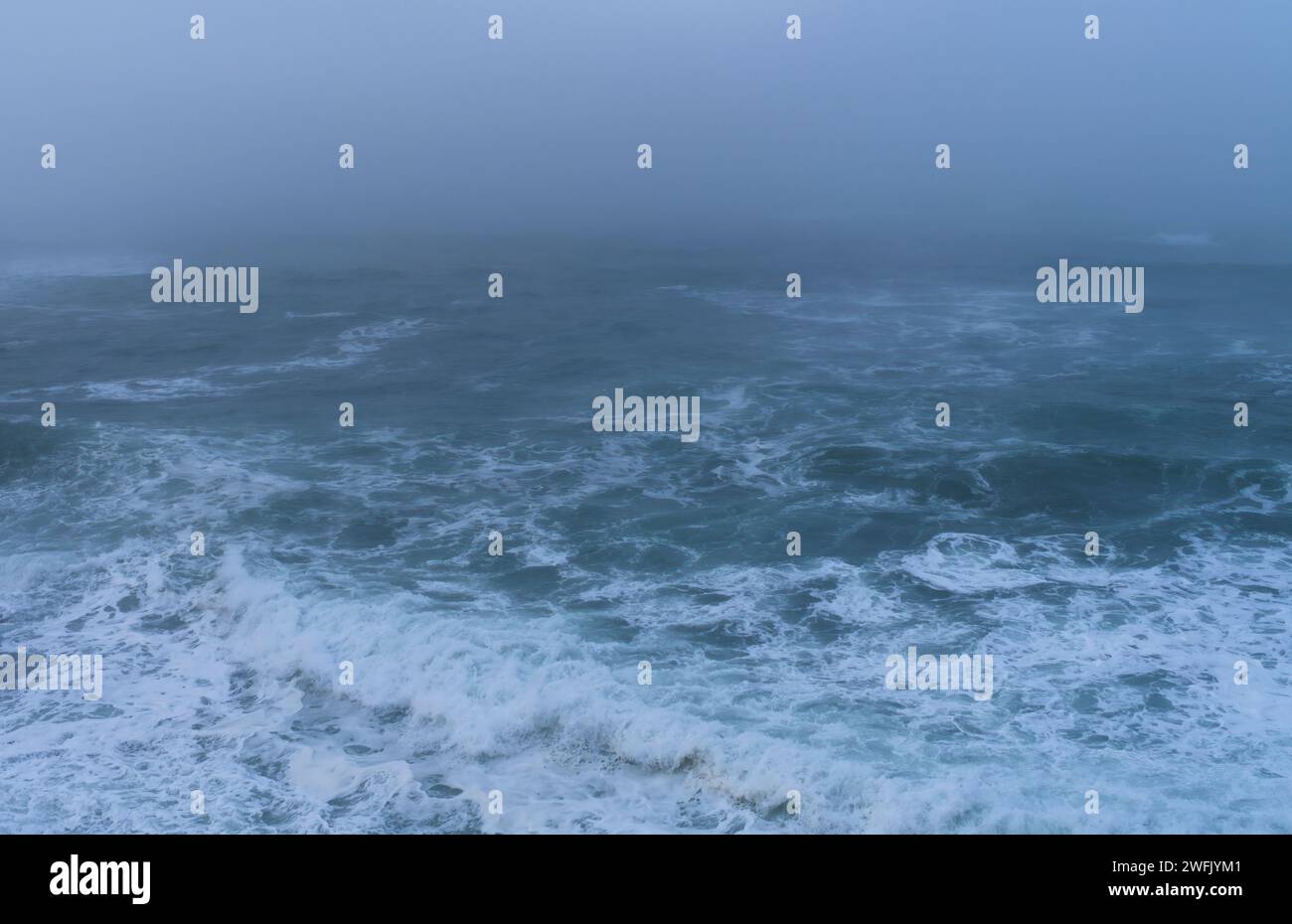 View of the foggy sea in winter on the coast of Cantabria, near the village of Comillas. Stock Photo