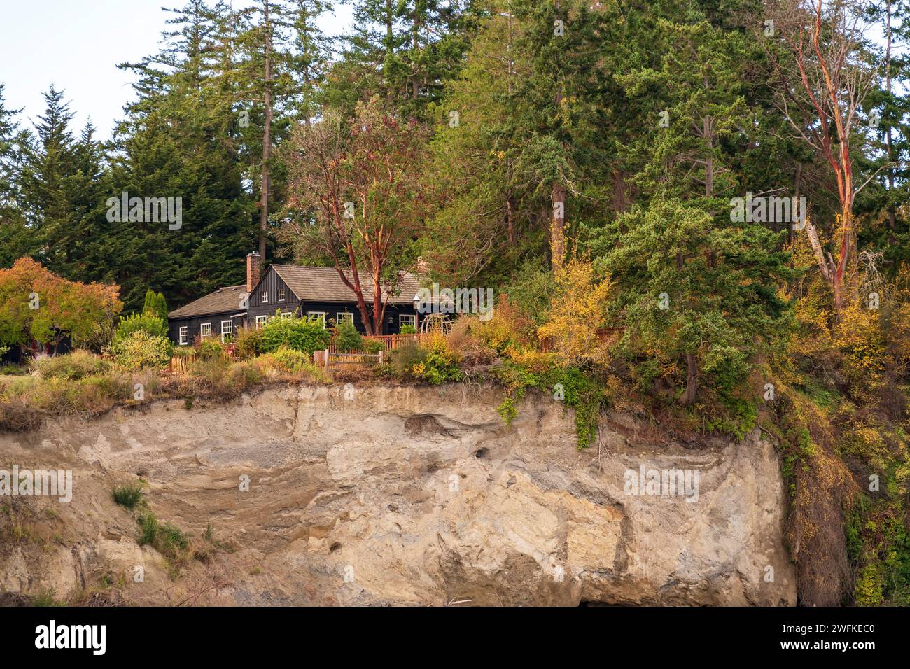 Horizontal photo of a black house sitting on a tree-covered bluff above Penn Cove at Coupevill, Whidbey Island, Washington State. Stock Photo