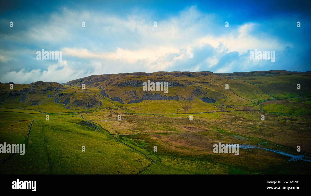 Scenic view of lush green fields leading up to a rugged mountain under ...