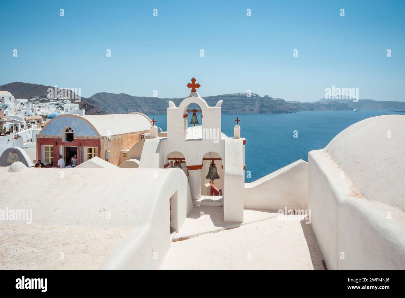numerous houses and church bells on the cliff of Santorini island. Oia village in the foreground and Cyclades islands in the background. Stock Photo