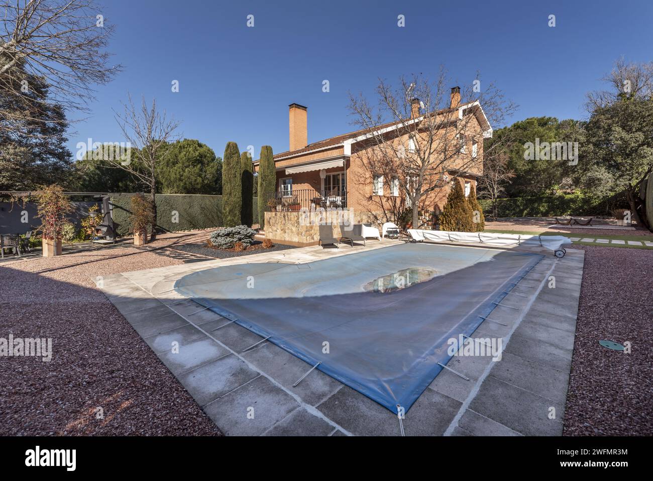 Gardens and outdoor recreation area of a single-family home with swimming pool covered with canvas and perimeter surrounded by hedges Stock Photo