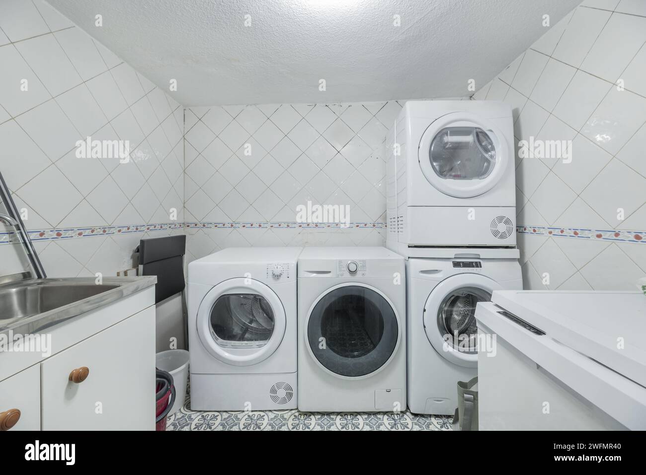 A room dedicated to laundry on the ground floor of a house full of washing machines and dryers Stock Photo