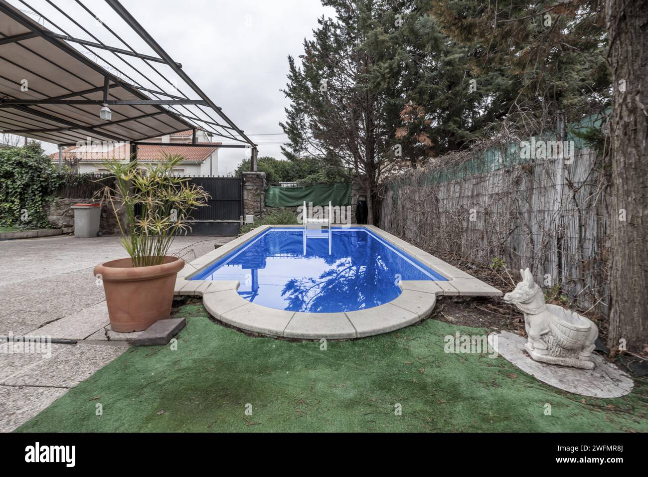 A small pool within a plot with a large awning with a metal structure Stock Photo