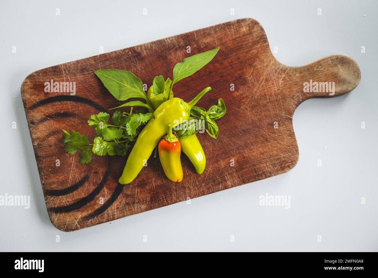 fresh chili peppers and herbs on rustic wooden cutting board, concept of simple natural healthy ingredients Stock Photo