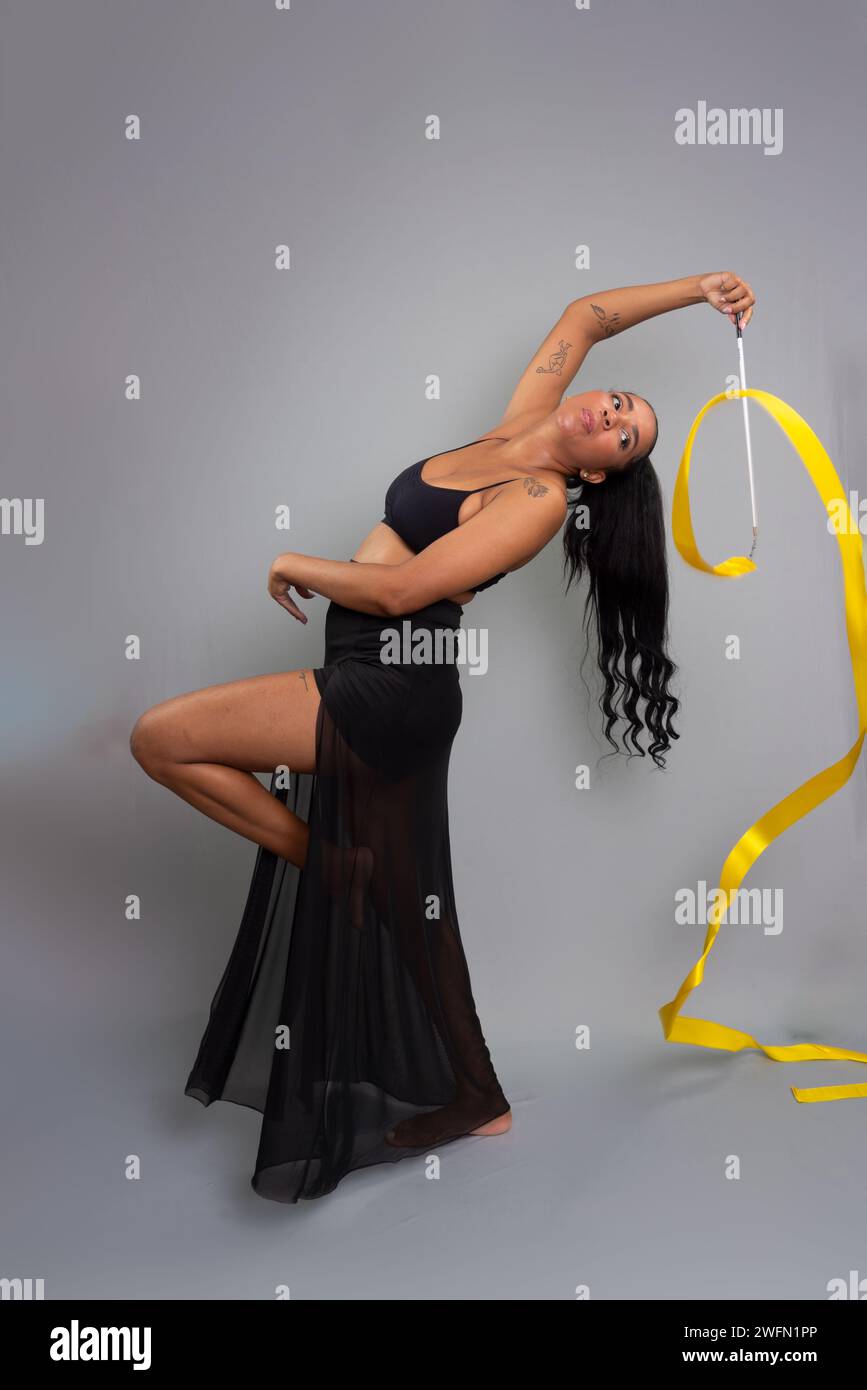 Beautiful gymnast woman doing acrobatic moves with a yellow ribbon ...