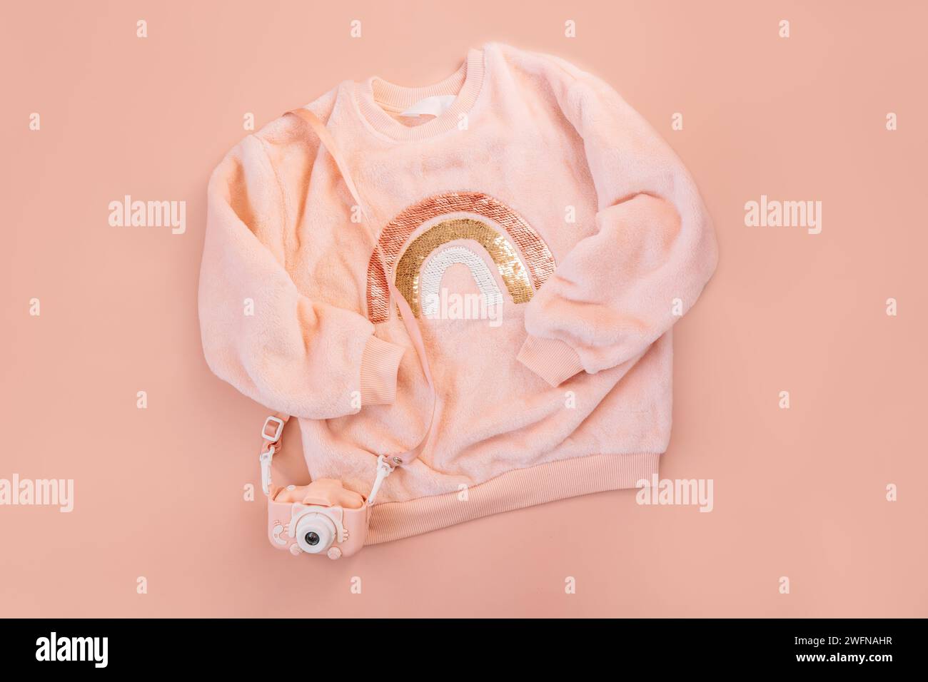 Children's pink sweater and digital camera on a pink background Stock Photo