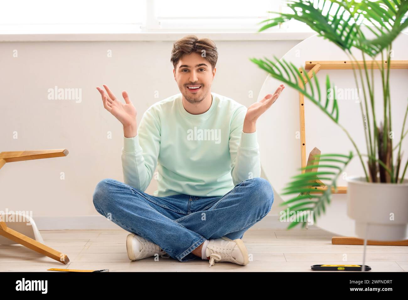 Young man assembling furniture in kitchen Stock Photo