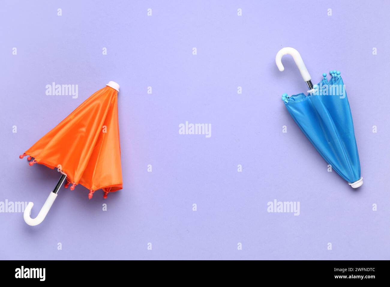 Mini stylish umbrellas on lilac background Stock Photo