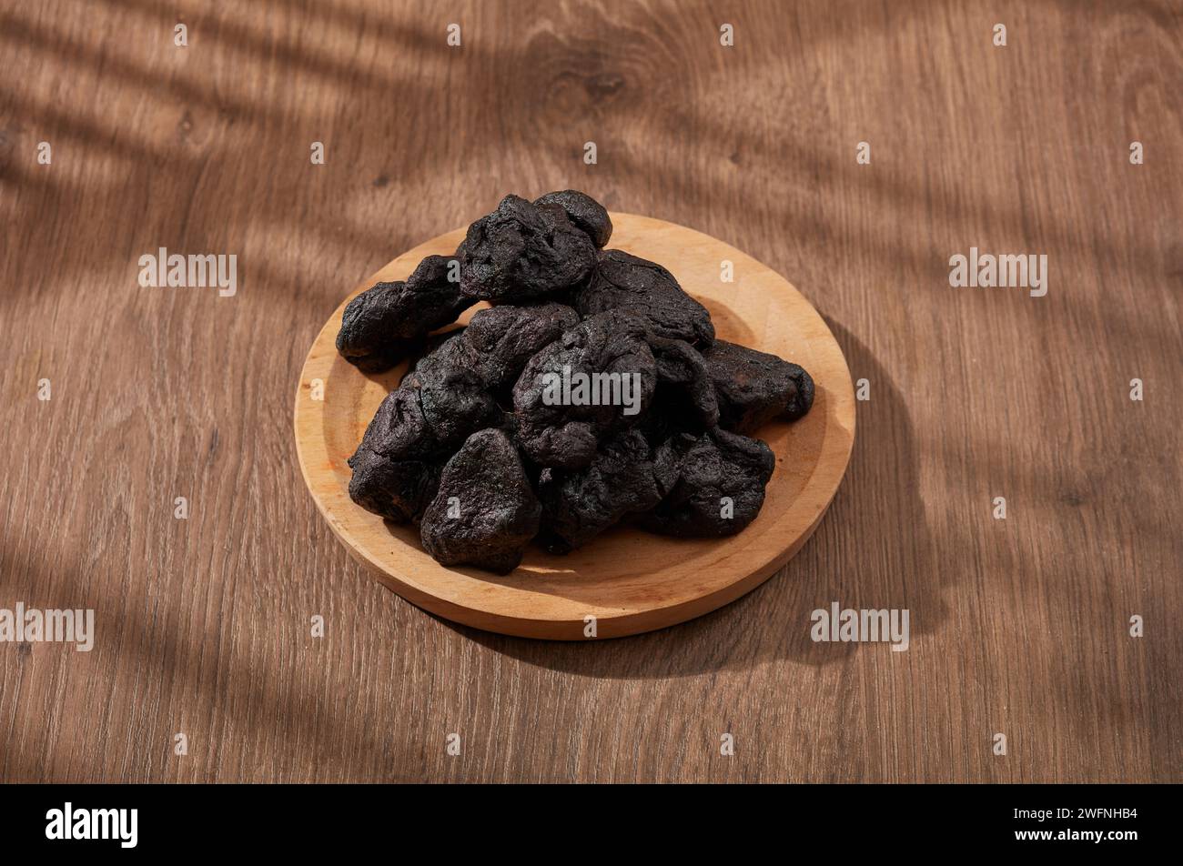 Radix rehmanniae putted on round wooden dish. Radix rehmanniae (Rehmannia glutinosa) is effective in both traditional and modern medicine, prevent ost Stock Photo