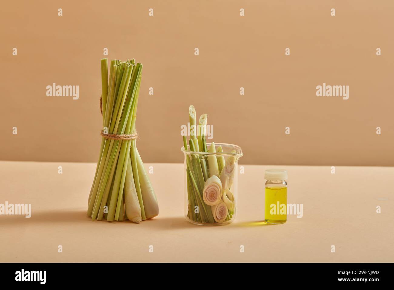 A bunch of lemongrass standing next to a glass jar of lemongrass. An empty label bottle containing essential oil extracted from lemongrass. Product mo Stock Photo