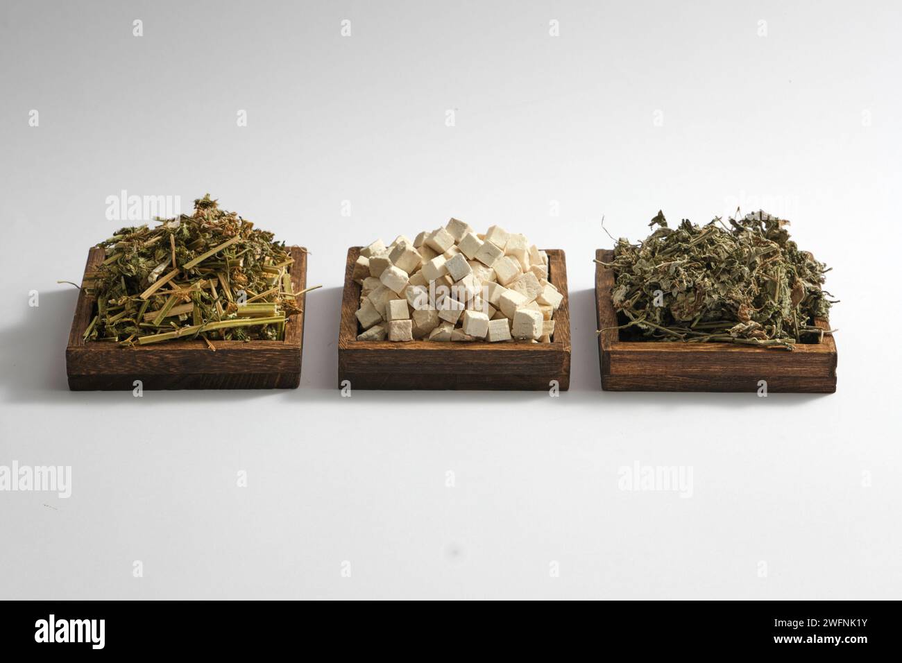 Some square wooden trays with Chinese motherwort, Poria cocos and Mugwort displayed on. White background. Herbs useful in treat health problems Stock Photo