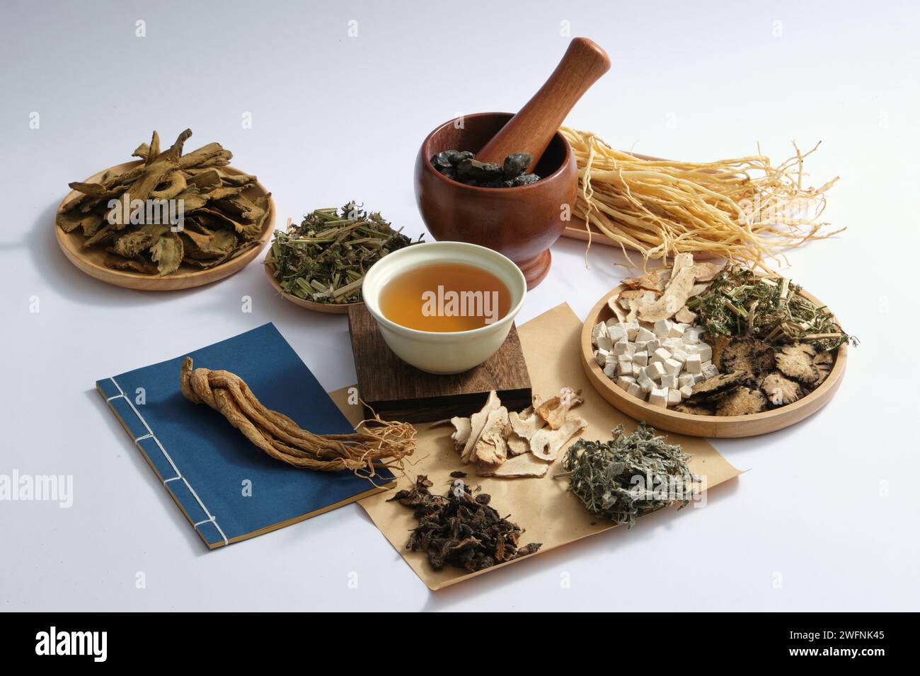 A bowl of medicine placed on a wooden podium in the center with many types of herb displayed around. Chinese medicine treat a wide range of ailments t Stock Photo