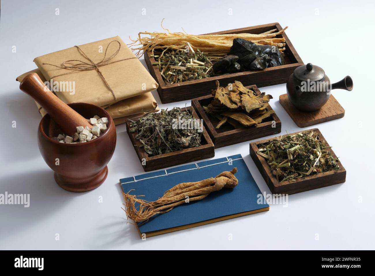 Some wooden trays with many types of herb placed on, displayed with earthen pot, medicine packs, ancient Chinese medicine books, mortar and pestle. Ch Stock Photo