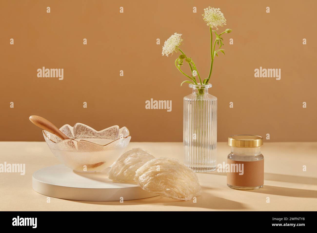 Glass transparent jar and bowl containing bird nest soup and a wooden spoon inside, few bird nests placed on round podium, Bird nest helps to anti-agi Stock Photo