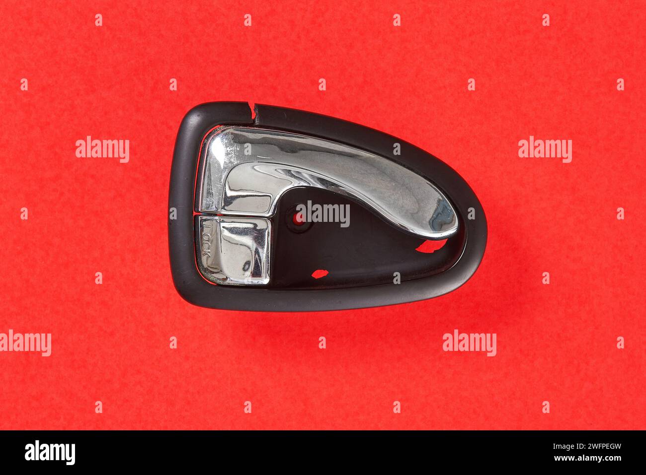 The right inner car door handle, which is damaged and needs to be replaced, is photographed with a red background Stock Photo