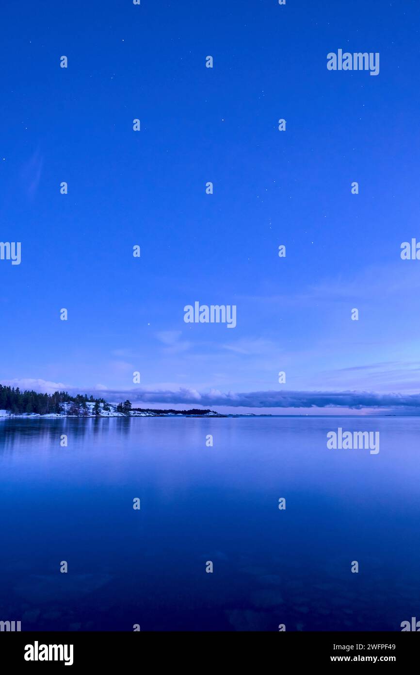A beautiful lake surrounded by distant trees under a starry night sky ...