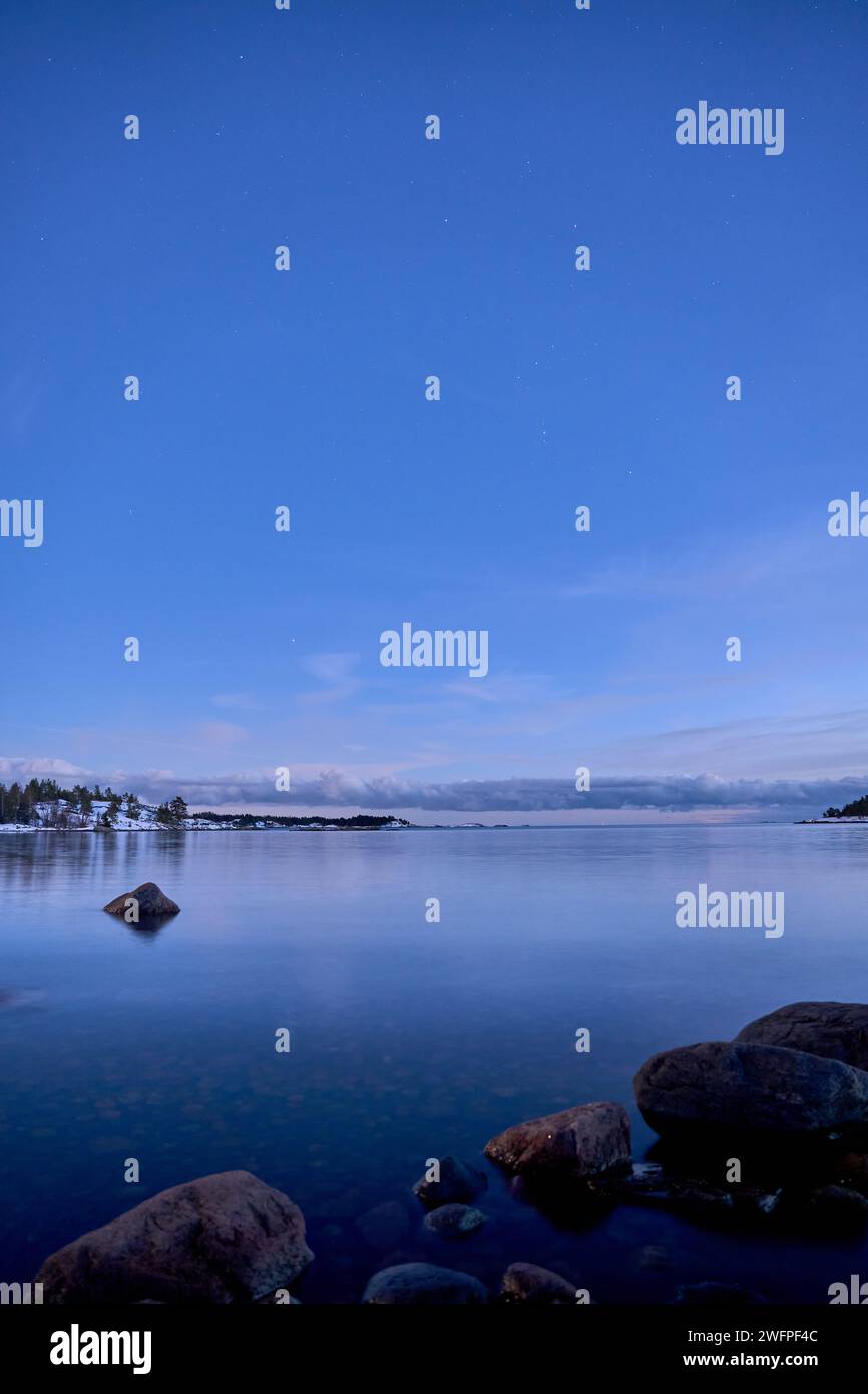 A beautiful lake surrounded by distant trees under a starry night sky ...