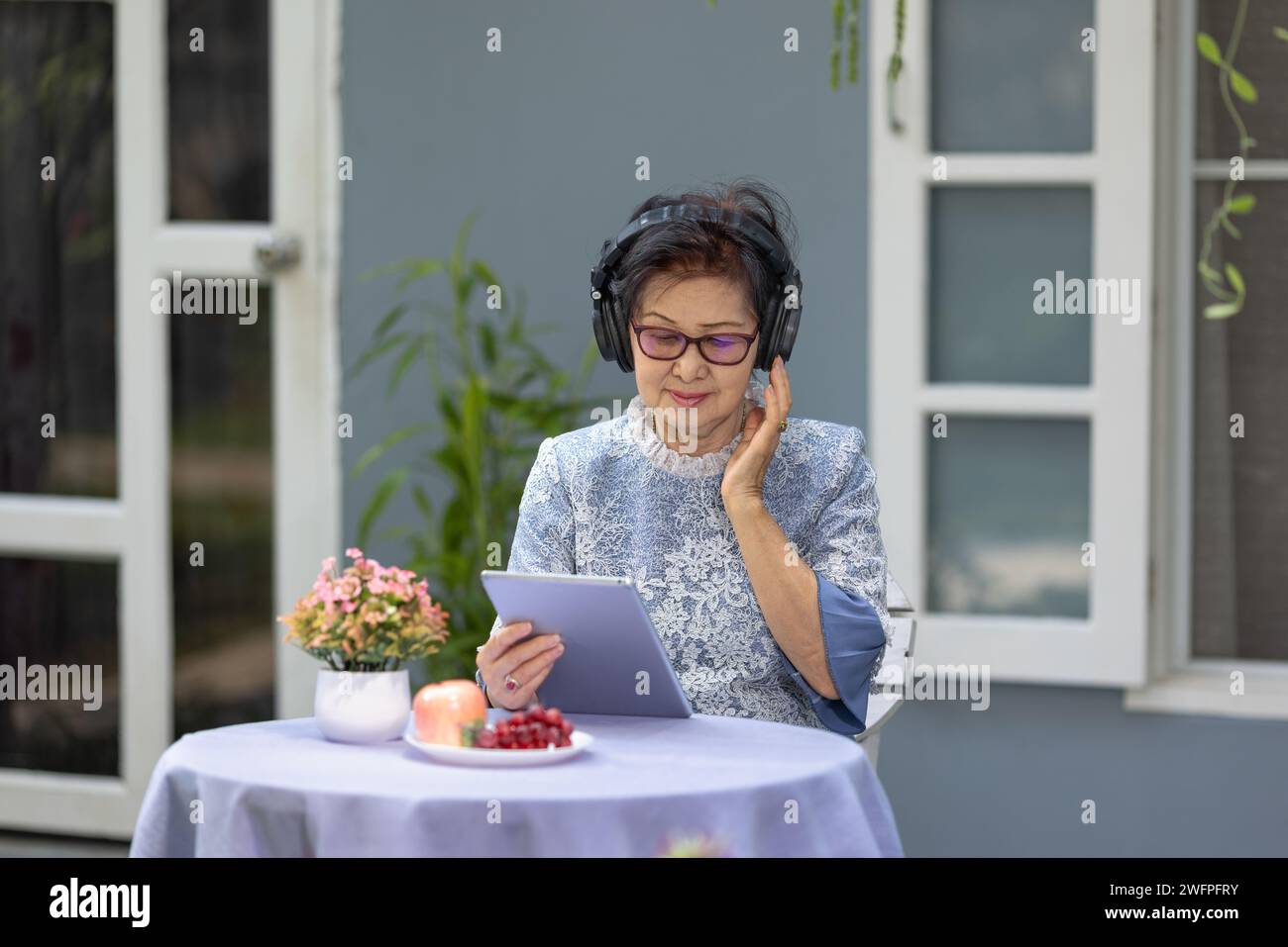 Senior woman is listen music and pose share good news at social media via  computer tablet Stock Photo