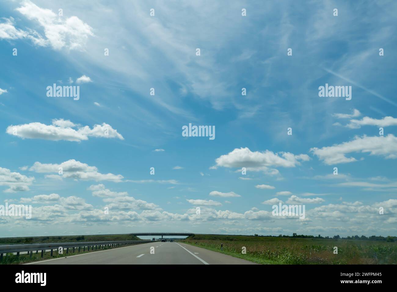 A road and a bridge under a slightly cloudy blue sky Stock Photo - Alamy