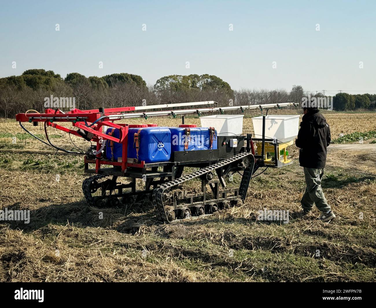 Shanghai. 25th Jan, 2024. This photo taken with a mobile phone on Jan. 25, 2024 shows an engineer maneuvering a farm robot in a field at Tinglin Township's Diantian Farm in east China's Shanghai. TO GO WITH 'Across China: Futuristic scene of robots taking over backbreaking farm jobs on horizon' Credit: Zhao Yihe/Xinhua/Alamy Live News Stock Photo