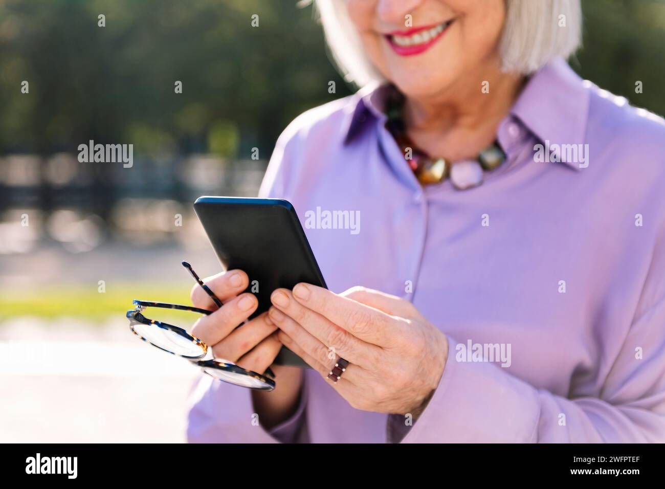 unrecognizable senior woman smiling using phone Stock Photo