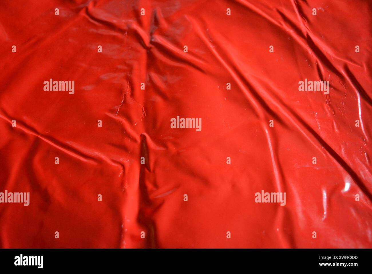 Red glossy fabric background, patent eco leather with pleats, wrinkles