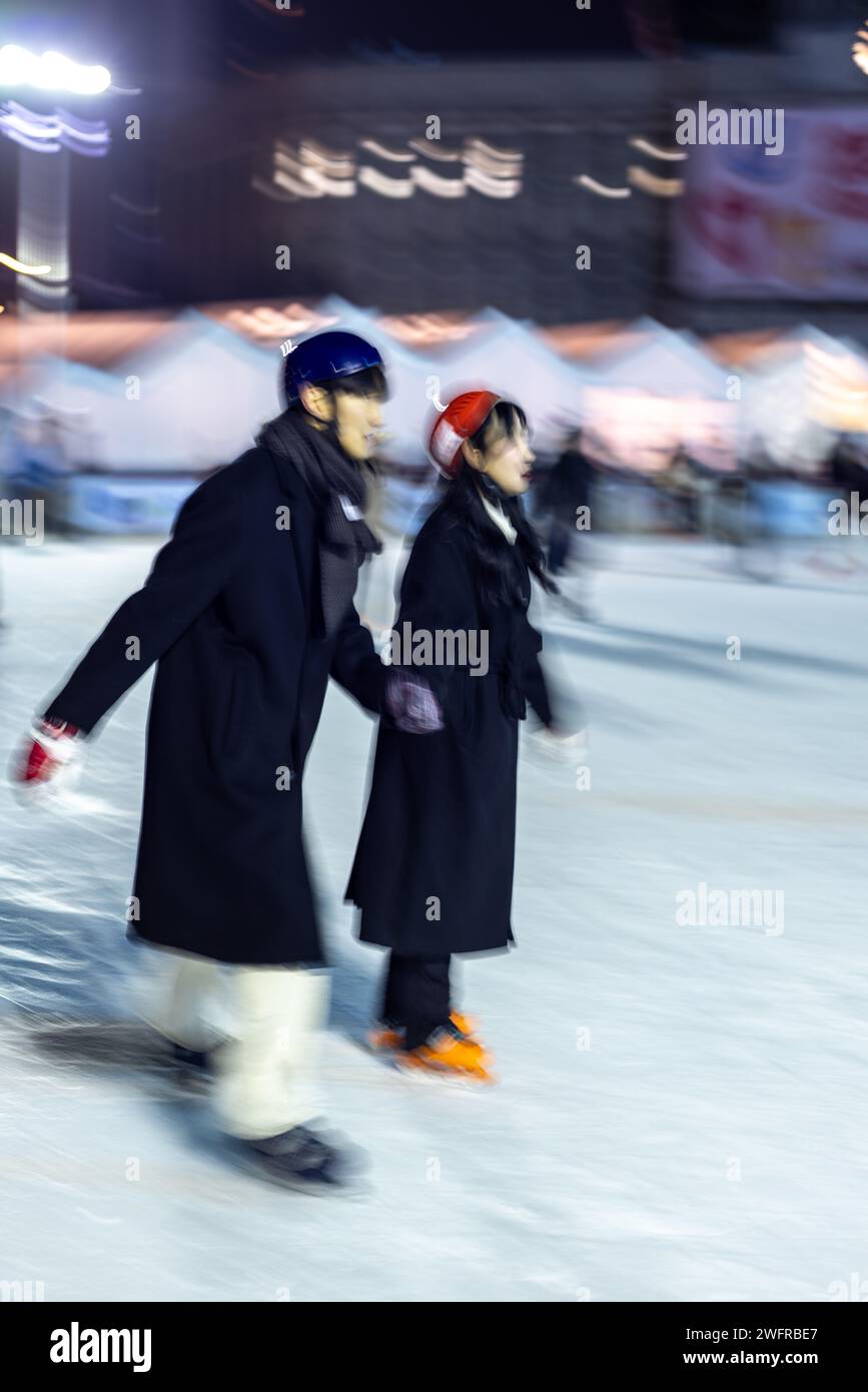 Intentional blur of people ice skating at night on the temporary ice skating ring in front of the City Hall in Seoul South Korea on 29 January 2024 Stock Photo
