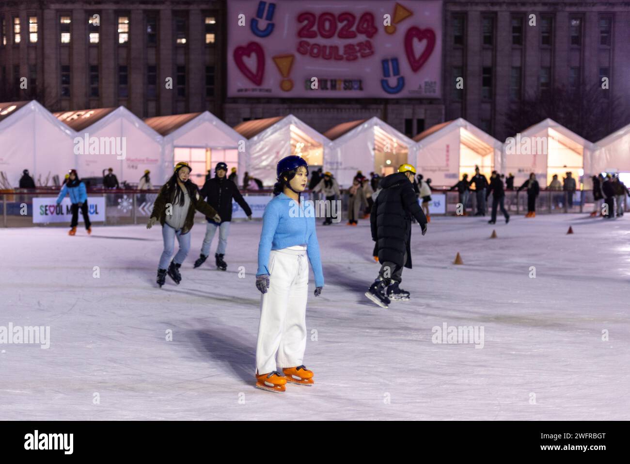 People ice skating at night on the temporary ice skating ring in front of the City Hall in Seoul South Korea on 29 January 2024 Stock Photo