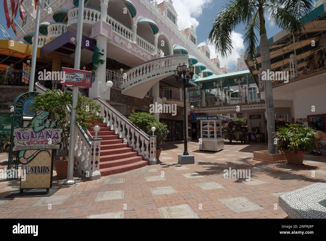 05/11/2010 - Aruba: This photograph showcases a lively open-air shopping plaza in Aruba, characterized by its colorful architecture, inviting stairway Stock Photo