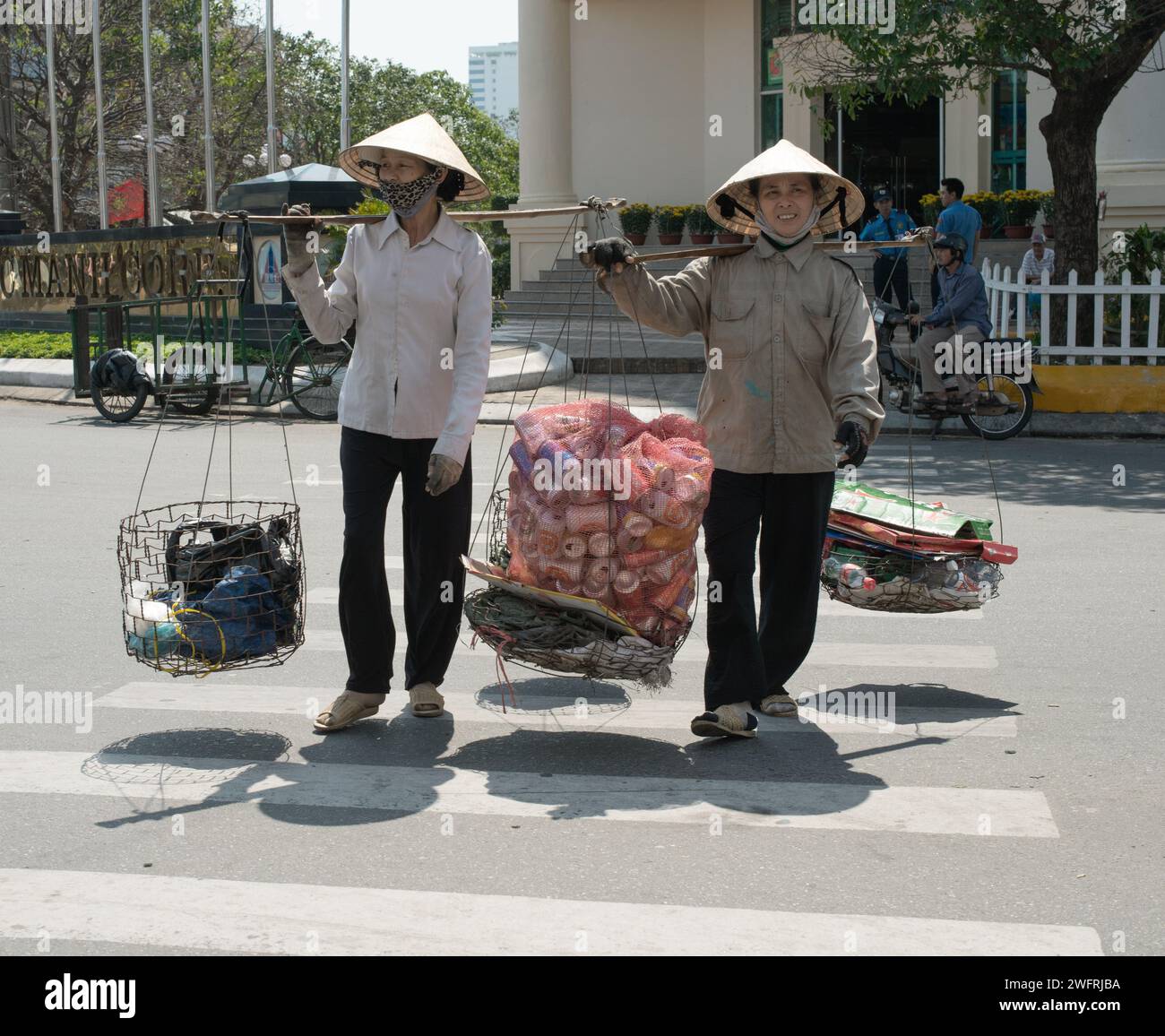 02/07/2014 - Saigon, Vieatnam: Two Vietnamese street vendors balancing goods on poles across their shoulders, a common sight in the bustling streets o Stock Photo