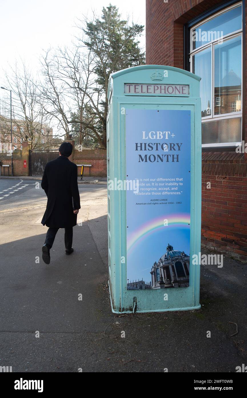 Eton, Windsor, UK. 1st February, 2024. An Eton College boy walks past a community library former telephone box outside the famous Eton College public school with a banner marking the LGBT+ History Month which starts today. The Headmaster of Eton College, Simon Henderson, nicknamed 'Trendy Hendy' has previously said that he is unashamedly “woke”. Last year he created a new role of 'director of inclusion education' to oversee diversity efforts at the school. Credit: Maureen McLean/Alamy Live News Stock Photo