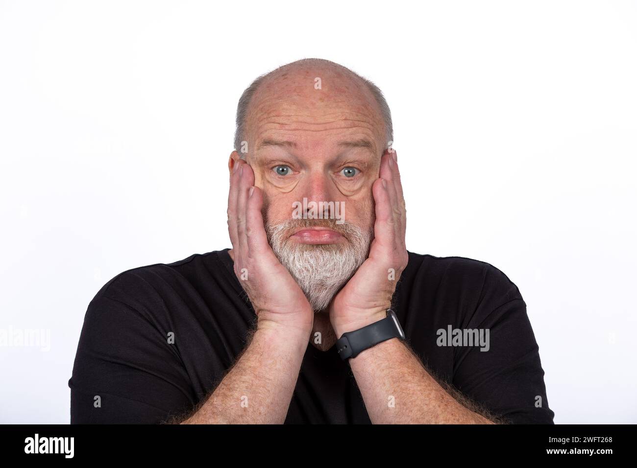 Stressed Middle-Aged Man in Black T-Shirt Expressing Shock and Despair on White Background Stock Photo