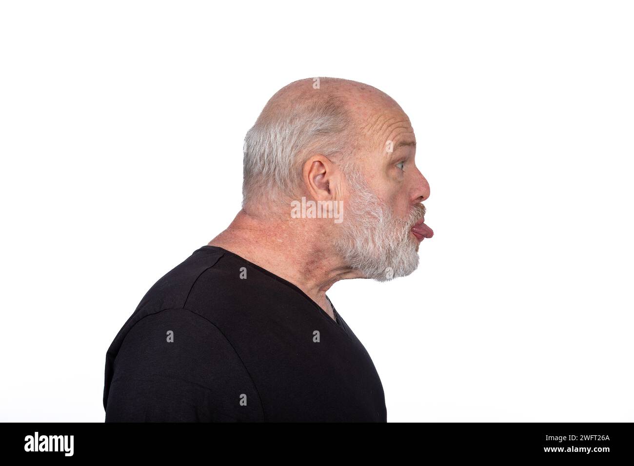 Profile Portrait, Middle-Aged Bearded Man in Black T-Shirt Sticking Out Tongue - Playful Humor on White Background Stock Photo