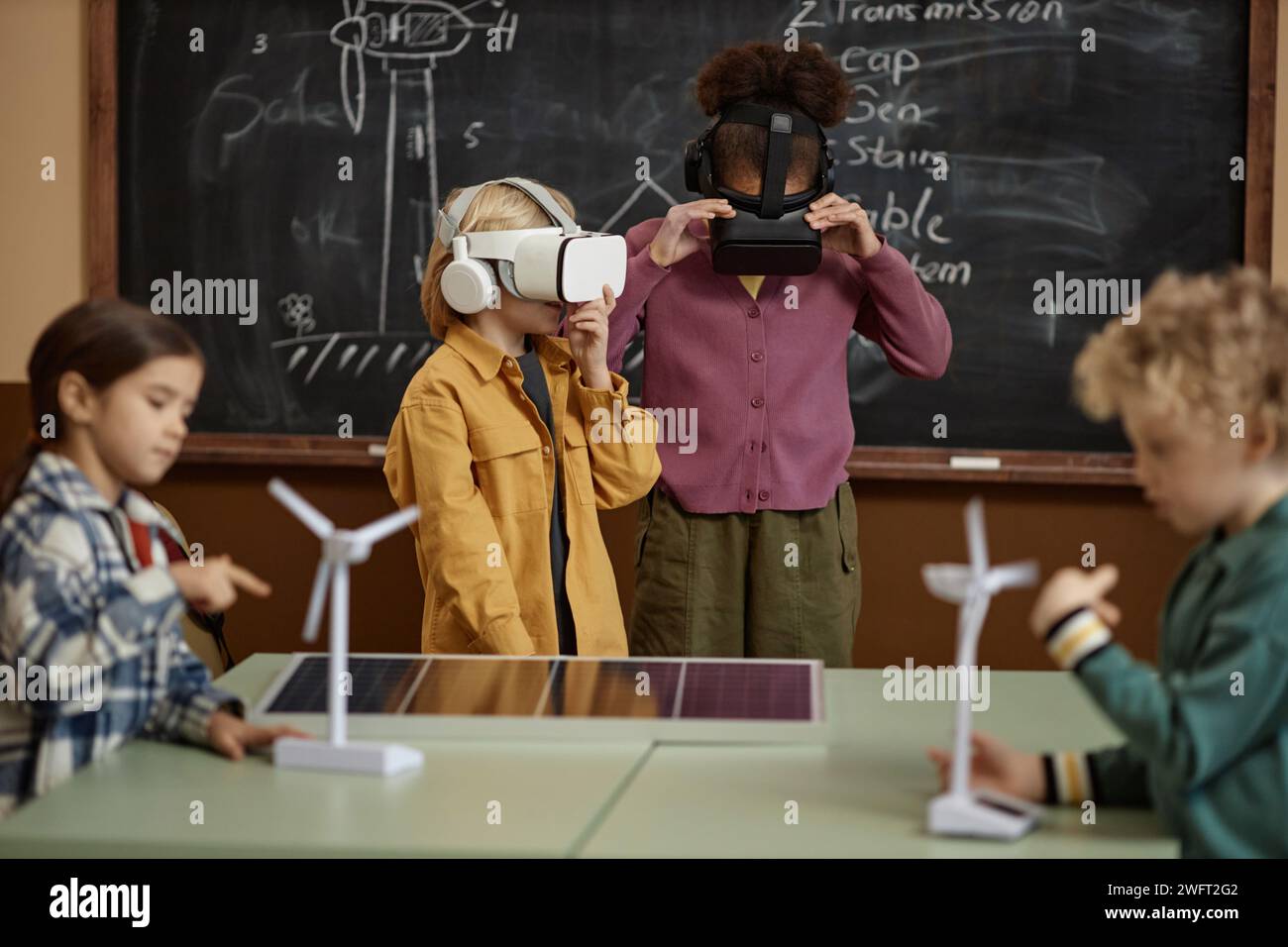 Portrait of two school children wearing VR headsets in class and learning about renewable energy Stock Photo