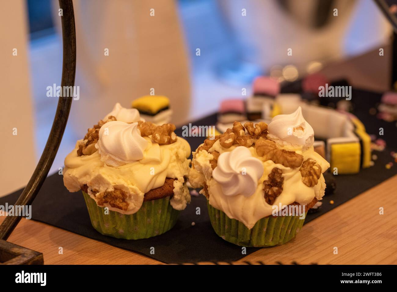 A pair of homemade coffee and walnut cupcakes topped with creamy coffee butter icing, walnut pieces and miniature meringues Stock Photo