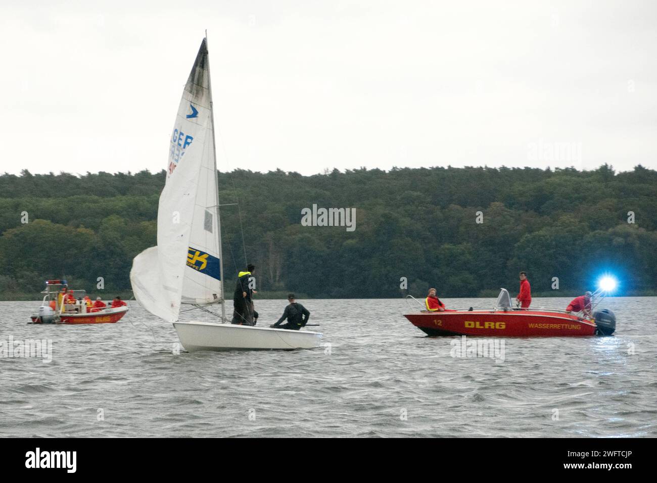 07.10.2023, Berlin, GER - Wasserrettung der DLRG kommt einem Segler auf dem Wannsee zur Hilfe. aussen, Aussenaufnahme, Berlin, Blaulicht, Blaulichteinsatz, Boote, deutsch, Deutsche Lebensrettungs Gesellschaft, Deutsche Lebensrettungsgesellschaft, Deutschland, DLRG, Ehrenamt, ehrenamtlich, Einsatz, Erste Hilfe, Europa, europaeisch, Gefahr, Gefahrensituation, Gewaesser, helfen, Helfer, Herbst, Hilfe, Jahreszeit, Lebensrettung, Menschen, Motorboot, Notfall, Notfallrettung, Personen, QF, Querformat, Regenwetter, regnerisch, retten, Retter, Rettung, Rettungsboot, Rettungsdienst, Rettungseinsatz, Re Stock Photo