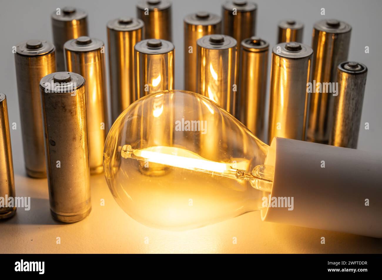 Light bulb turned on, with batteries next to it. Accumulation and reuse