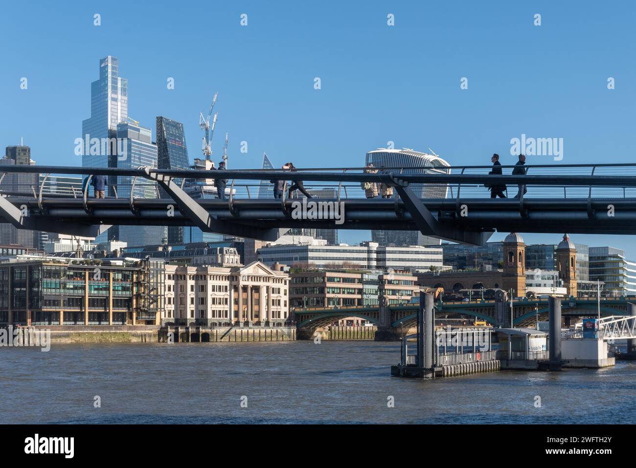 People walking across the Millennium Bridge over the River Thames in London, England, UK, on a sunny winter day Stock Photo