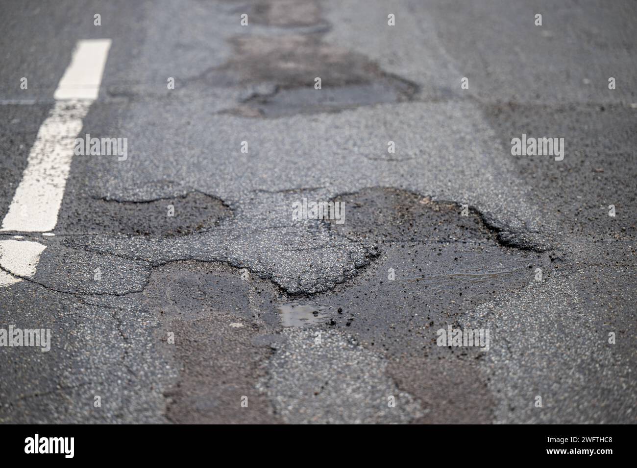 , Alltag, 01.02.2024,  Detailaufnahme eines Schlaglochs in einer asphaltierten Straße, umgeben von Rissen und beschädigtem Belag. Die Textur des Aspha Stock Photo