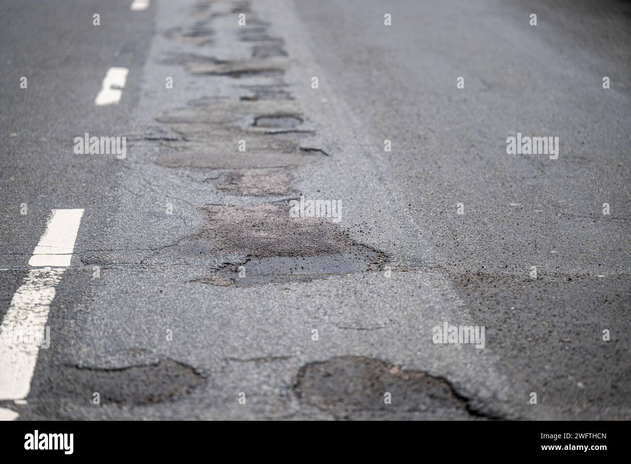 , Alltag, 01.02.2024,  Detailaufnahme eines Schlaglochs in einer asphaltierten Straße, umgeben von Rissen und beschädigtem Belag. Die Textur des Aspha Stock Photo