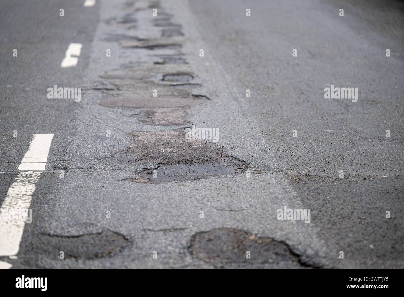 Asphaltstraße mit Schlagloch und Rissen , Alltag, 01.02.2024, Detailaufnahme eines Schlaglochs in einer asphaltierten Straße, umgeben von Rissen und beschädigtem Belag. Die Textur des Asphalts und das stehende Wasser im Schlagloch sind deutlich sichtbar. *** Asphalt road with pothole and cracks , Everyday life, 01 02 2024, Close-up of a pothole in an asphalt road, surrounded by cracks and damaged pavement The texture of the asphalt and the standing water in the pothole are clearly visible Stock Photo