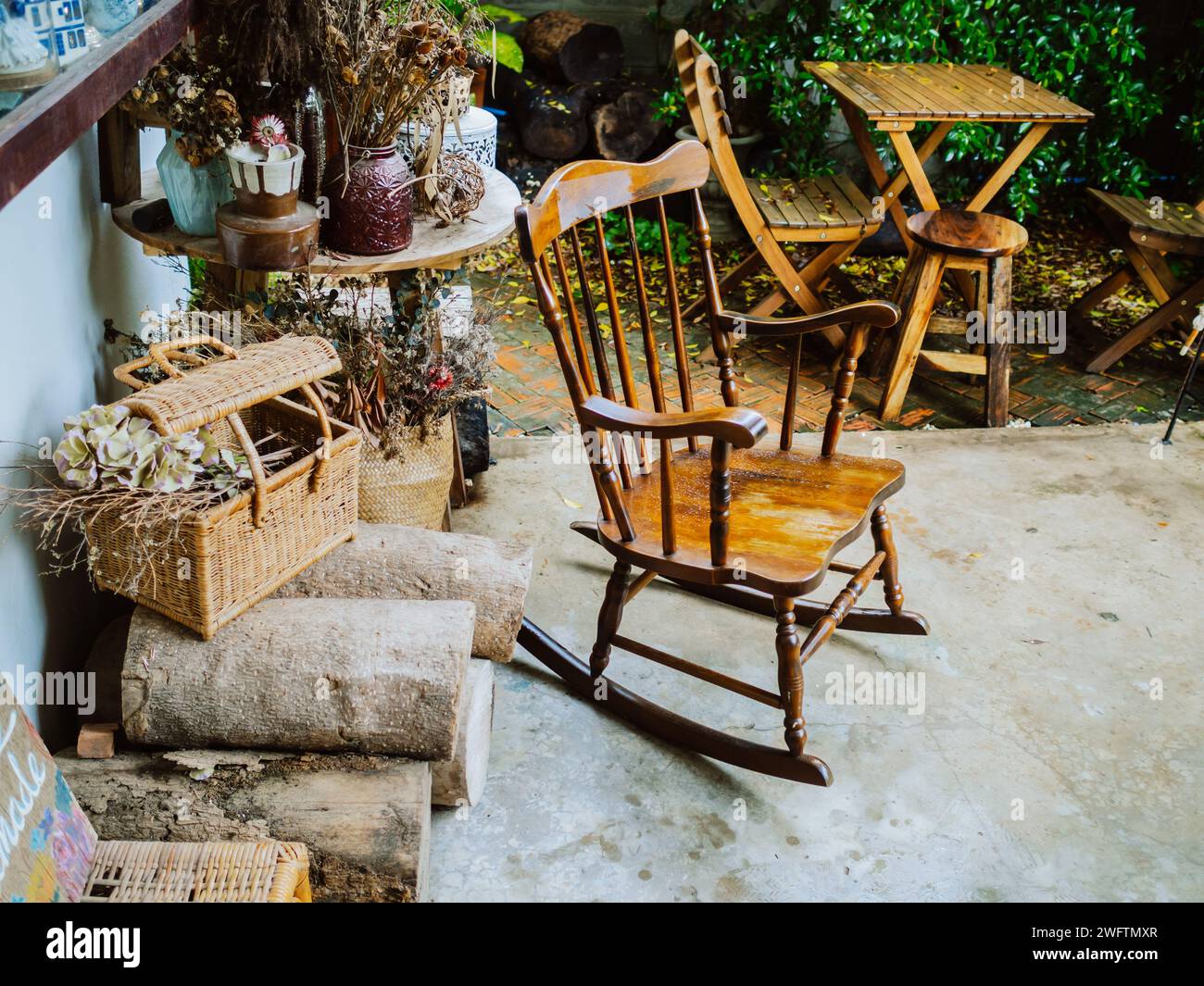 a rocking chair on a rustic porch overlooking a blooming garden. On a wooden porch overlooking a field, rocking chairs invite relaxation Stock Photo