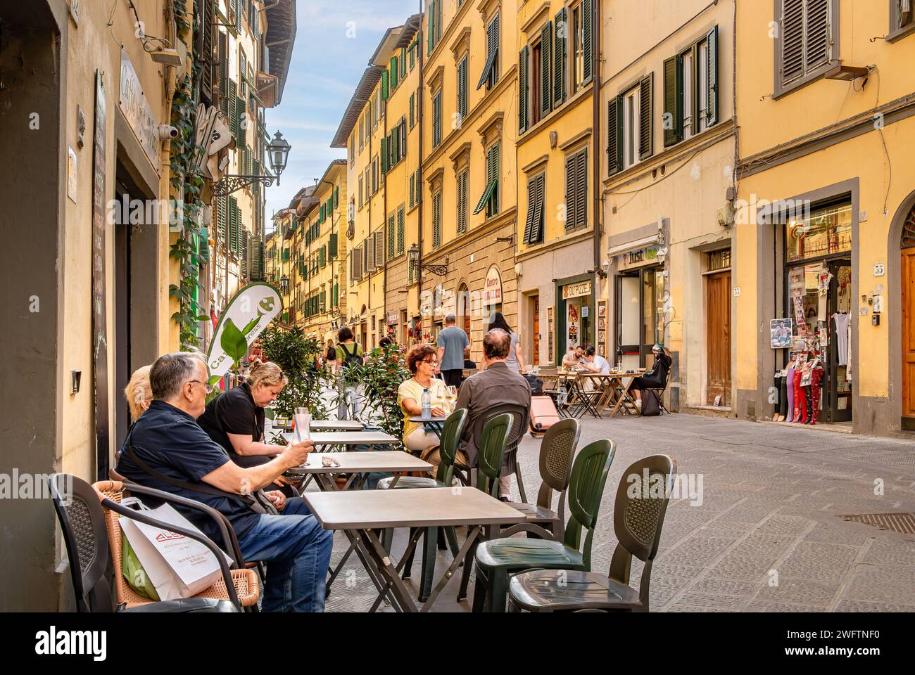 People enjoying drinks outside a cafe on Via Faenza , a lively street with many restaurants and