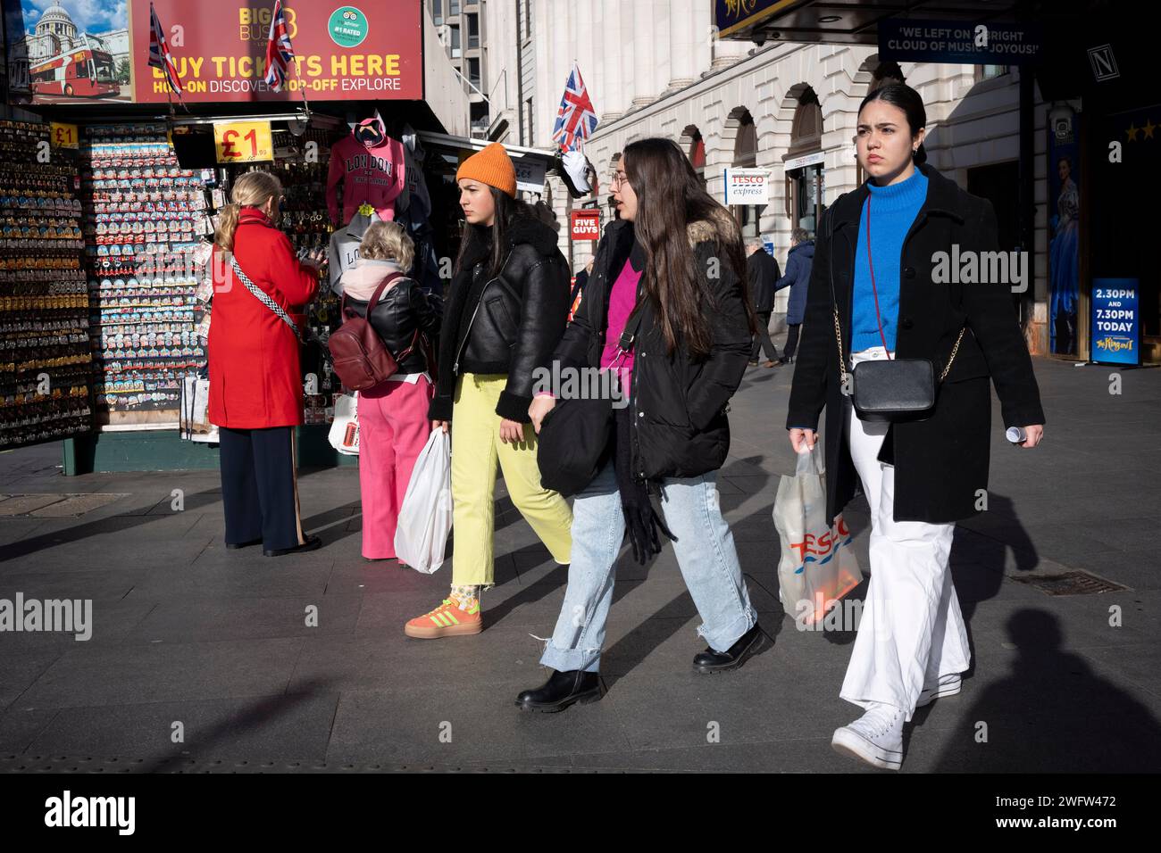 Young women shoppers walk past a tourist souvenir kiosk on Tottenham Court Road in the West End, on 1st February 2024, in London, England. Stock Photo