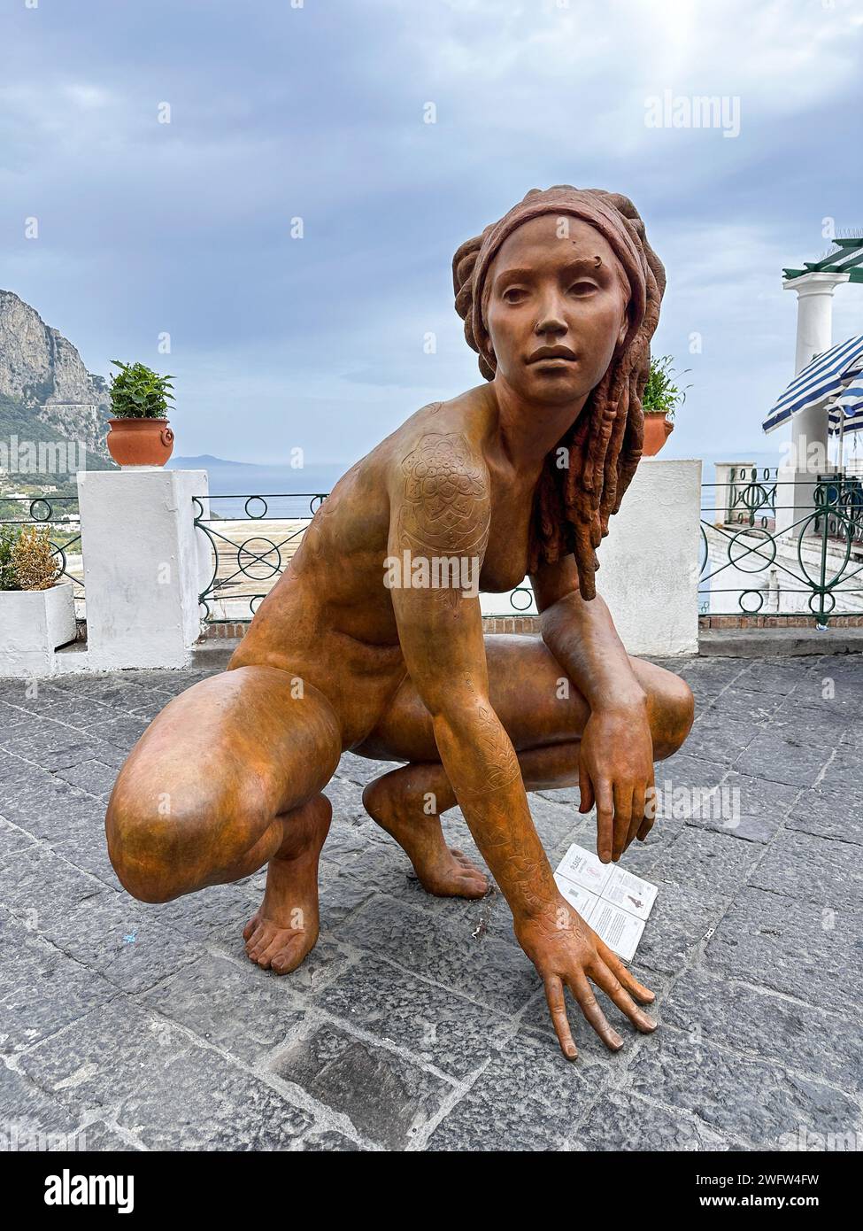 A sculpture on the ground near flowers and rocks in Capri, Italy Stock Photo