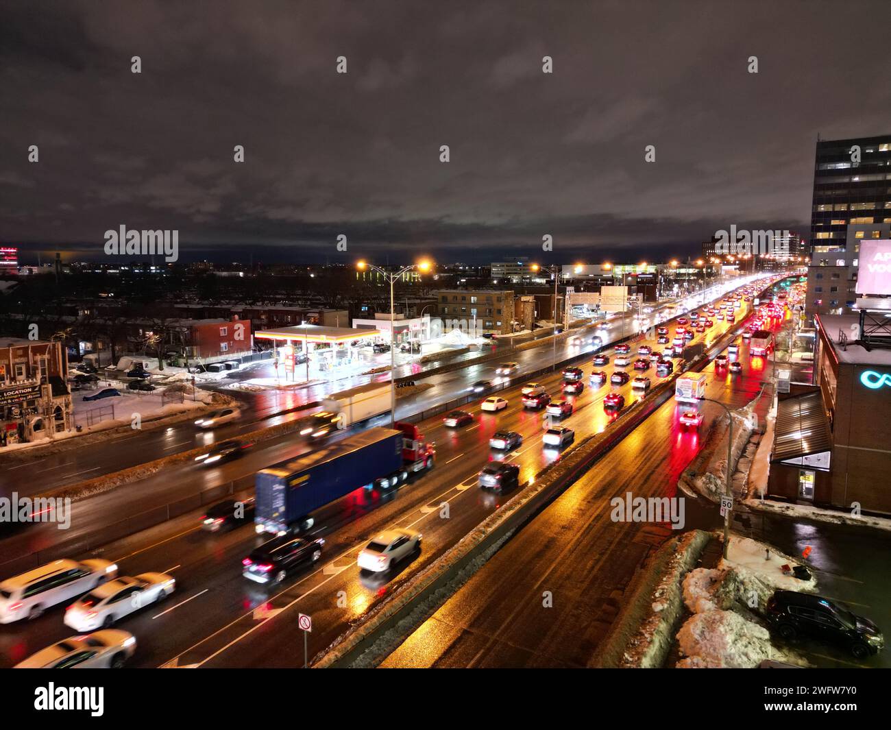 A bustling cityscape at night as numerous cars traverse the illuminated highway Stock Photo